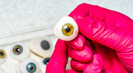 Ophthalmologist or surgeon holds an eye, eyeball prosthesis in hands . Concept photo for ocular...