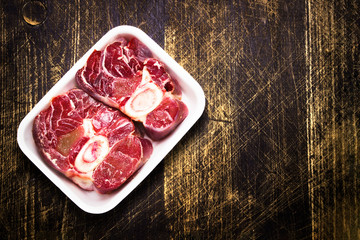 Raw ossobuco meat, two beef steak for cooking, black wood background. a traditional dish of Italian cuisine, which is a veal shank.Top view. Copy space