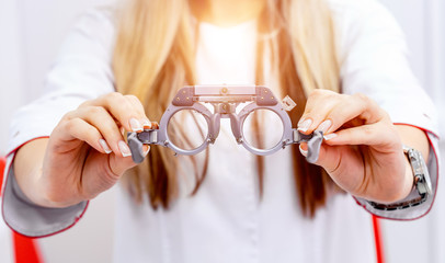 Close up of a phoropter in woman's hands, ophthalmologist in a blurred background. tool for ophthalmologists. Vision correction