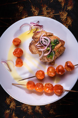 Food still life on a tray on a white plate baked meat and tomatoes on skewers decorated with red onions and olive oil