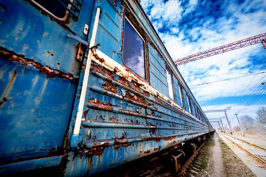 old rusty weathered peeled paint of an old wagon. Blue abandoned railway carriage. Old railwaystation.