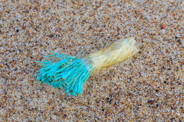 Environmental pollution - a part of an old blue rope, brought back by the sea as garbage