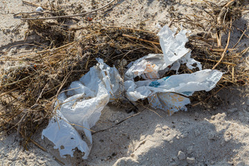 Environmental pollution - a shred  of plastic, lying on the beach as waste