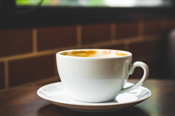 close up modern hot black coffee the cappuccino on wood background with coffee bubble foam pattern and texture in white cup looking and feel so delicious on glasses table in coffee shop.