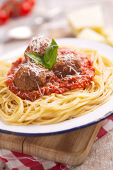 Spaghetti with meatballs and parmesan cheese on a rustic table