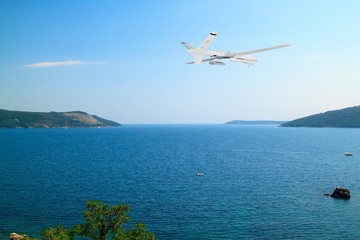 Fototapeta na wymiar unmanned RC military drone flies over calm sea with beautiful white clouds on blue sky