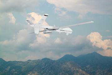 Fototapeta na wymiar unmanned RC military drone flies over mountains with white clouds on a blue sky background