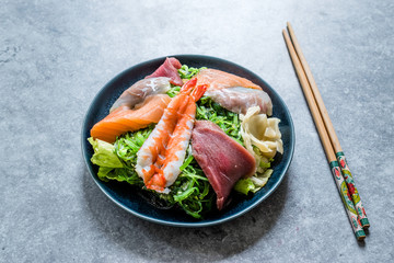 Sashimi Salad with Wakame, Seaweed, Salmon, Sea Bass, Shrimp, Kani, Mackerel Fish, Tuna served with Chopsticks.