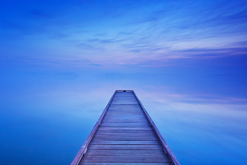 Jetty on a still lake at dawn in The Netherlands
