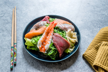 Sashimi Salad with Wakame, Seaweed, Salmon, Sea Bass, Shrimp, Kani, Mackerel Fish, Tuna served with Chopsticks.
