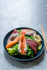 Sashimi Salad with Wakame, Seaweed, Salmon, Sea Bass, Shrimp, Kani, Mackerel Fish, Tuna served with Chopsticks.