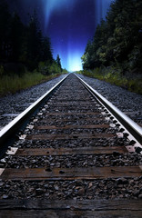 Looking down train tracks at night with Northern Lights in Sky, Alberta, Canada