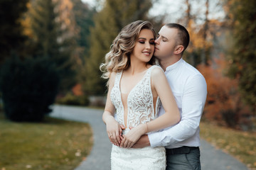 Obraz premium Loving couple in stylish wear hugs in the park in the autumn season. Autumn. Golden autumn. Golden leaves. Portrait of happy young couple outdoor