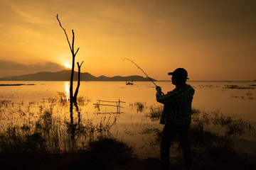 Fisherman at lake on sunset,silhouette