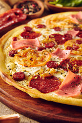 Meat and tomato pizza on wooden table close up