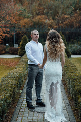 Fototapeta premium Man with girlfriend embracing her in a park. True love among lovers. Sincere emotions and love on the planet. Beautiful woman with make up and hairstyle. Young couple in love on a autumn day. 