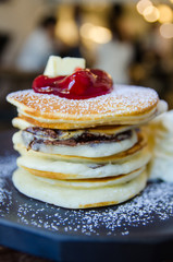 stack of pancake with strawberry on top on black plate