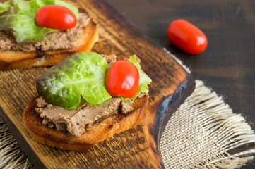homemade meat pate on toasted crusty bread. dark photo style.
