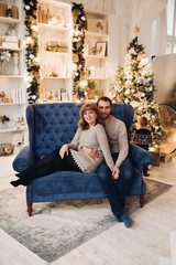 Obraz premium Portrait of loving mother and father holding their cute and adorable son wearing winter patterned sweater. They are smiling under snowfall at Christmas.