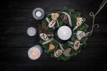 christmas, advent table wreath on a dark, wooden, rustic table with four candles lit up decorated with natural ornaments, nordic  style, home decoration, background