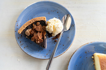Overhead flatlay view of a slice of chocolate pecan pie with vanilla ice cream and a spoon on a blue plate