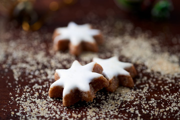 Christmas cookies (cinnamon stars) and brown sugar on dark background. Close up. 