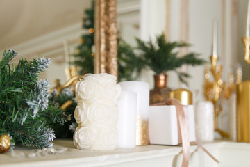 Christmas garland on a marble white fireplace. Decor of white, gold balls, Christmas tree, red bows, in the interior for the new year.Festive home decoration