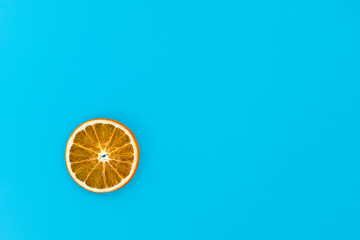 Christmas greeting card with a dried slice of orange on a blue background. Homemade decoration. Top view, copy space.