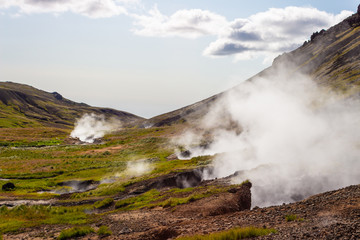 Geothermal hot springs steaming and smoking in the mountains, valley, foothill