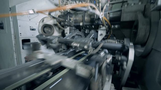 Factory machine pushes printed books on a conveyor.