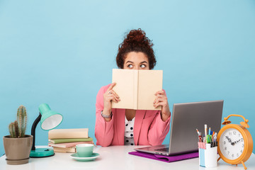 Image of confused woman holding book and looking aside while working