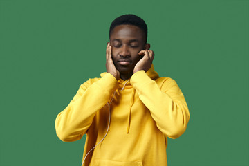 young black man in yellow hoodie listens to music