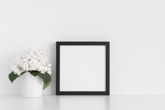 Black square frame mockup with a hortensia in a pot on a white table.