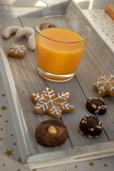 Group various kinds of delicious sweet Christmas cookies on light gray wood, fresh orange juice, tasty holiday breakfast