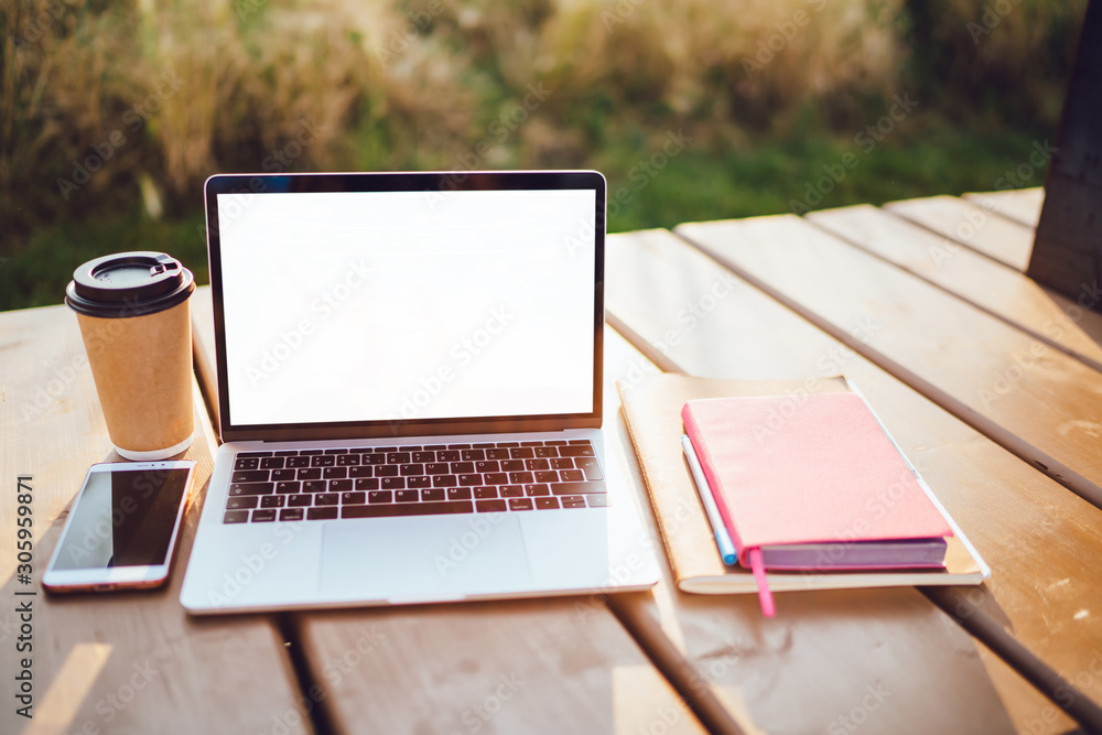 Poster open laptop computer with mock up blank copy space screen standing outdoors on wooden table with tak