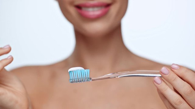 cropped view of woman applying toothpaste on toothbrush 