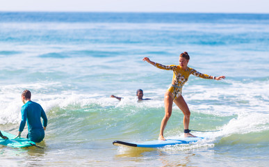 Girl learns to stand on surfboard. Water sport activity. Sri Lanka