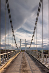 Dramatic empty road cable bridge, suspension bridge cloudy sky by sunset,