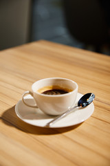 selective focus of cup with hot coffee on wooden table in cafe