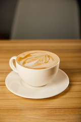 tasty cappuccino in white cup with saucer on table