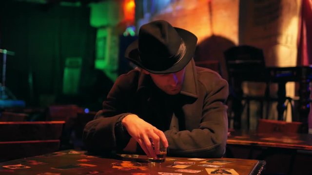lonely man sits himself in a dark bar with a glass of whiskey where he came after work