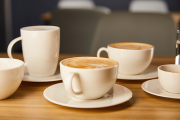 selective focus of saucers with white cups of tasty coffee in cafe