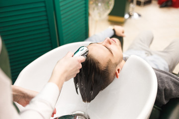 Obraz na płótnie Canvas Hairdresser washes a client’s hair before cutting