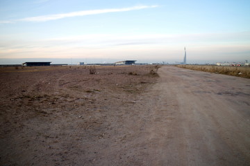 Temporary road to the construction site on the outskirts of the city in autumn twilight