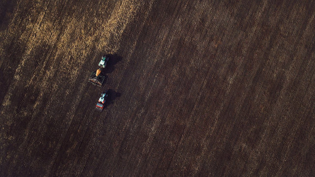 Two Tractors On The Field Sowing Wheat