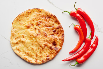 Top view of imereti khachapuri with chili peppers on marble texture