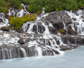 Fototapeta premium Waterfall in the forest, cascading water into a glacial river