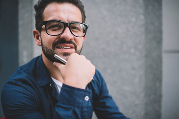 Portrait of handsome Caucasian man student with pen in hand looking at camera during education time on urban setting, good looking male journalist in optical spectacles for provide eyes protection