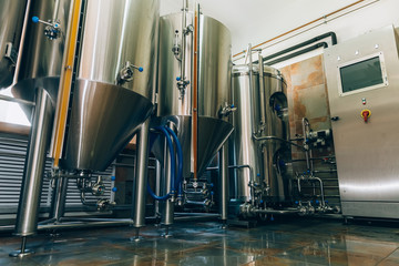 Microbrewery equipment. Close up tanks in brewery warehouse. Metal brewery vessels. Small business concept.