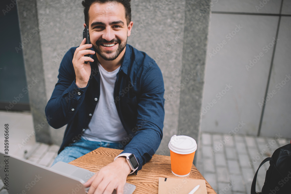 Aufkleber portrait of cheerful male programmer looking at camera while calling to friend for talking, happy sk